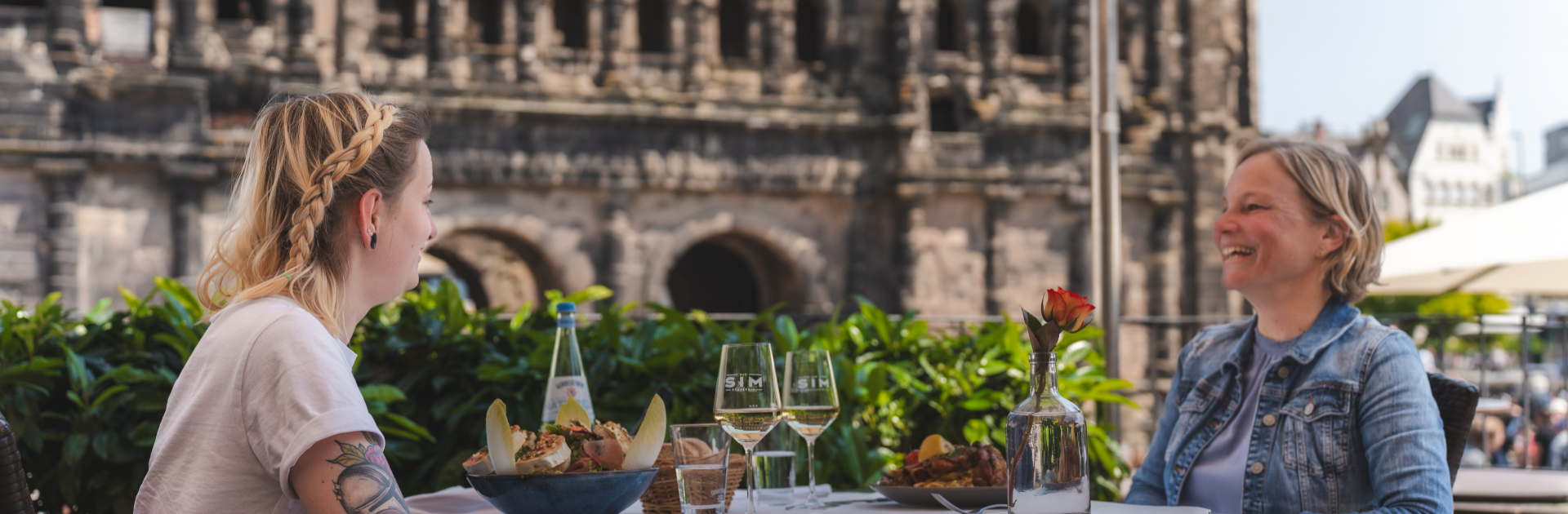 Two women in a restaurant in front of the Porta Nigra - © Crastulo Media / Trier Tourismus und Marketing GmbH