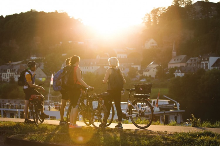 Eine Gruppe mit Fahrrädern auf dem Moselradweg in Trier während des Sonnenuntergangs - © Melanie Reuss / Trier Tourismus und Marketing