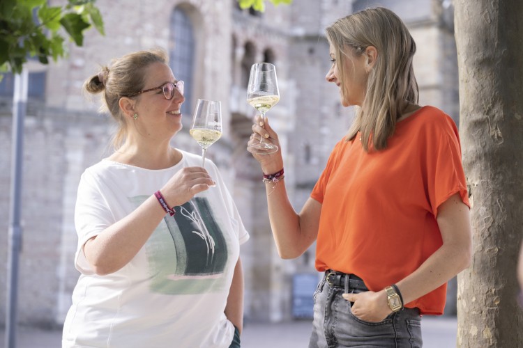Deux femmes boivent du vin devant la cathédrale de Trèves - Le circuit du vin de la Moselle à la rencontre de l'histoire - © Victor Beusch / Trier Tourismus und Marketing GmbH